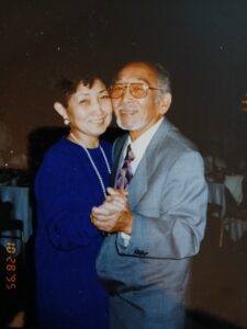 A photo of Joe and Flora Arai standing together, smiling warmly.